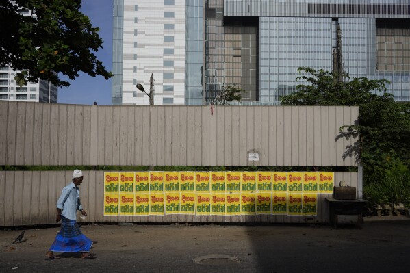 A Muslim man walks past a wall pasted with election propaganda of the main opposition candidate in the upcoming presidential election in Colombo, Sri Lanka, Friday, July 26, 2023. (AP Photo/Eranga Jayawardena)