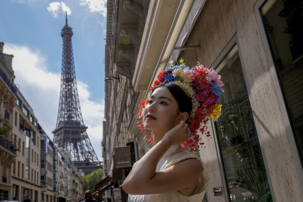 Hu Xiao, from China, poses as her friends take her photograph near the Eiffel Tower at the 2024 Summer Olympics, Sunday, July 28, 2024, in Paris, France. (AP Photo/Yasin Dar)