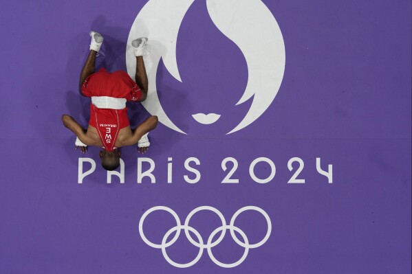 Sweden's Nebil Ibrahim kisses the mat after defeating Palestinian boxer Wasim Abusal in their men's 57 kg preliminary boxing match at the 2024 Summer Olympics, Sunday, July 28, 2024, in Paris, France. (AP Photo/John Locher)