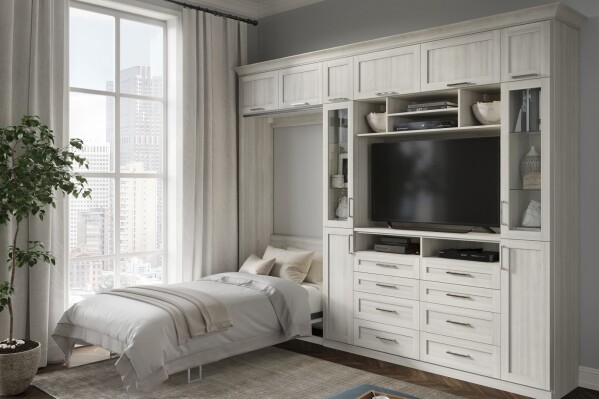 This image provided by California Closets shows a room with a bed built into a cabinet. A horizontal tilt wall bed with built-in cabinets for TV and more helps organize a studio apartment and keeps the sleeping area in its own space. (California Closets via AP)