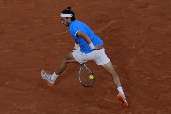 Lorenzo Musetti of Italy returns a shot to Felix Auger-Aliassime of Canada during their men's singles bronze medal match, at the 2024 Summer Olympics, Saturday, Aug. 3, 2024, at the Roland Garros stadium in Paris, France. (AP Photo/Andy Wong)