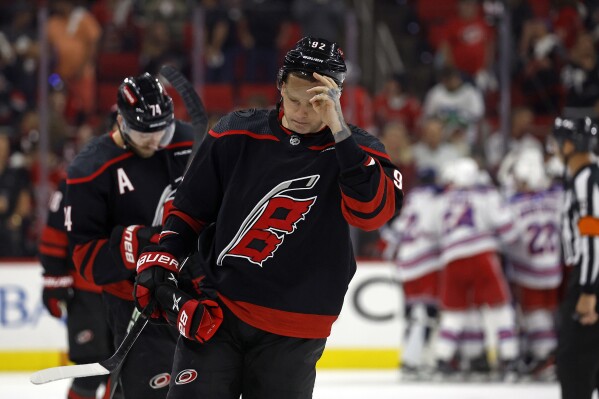 FILE- Carolina Hurricanes' Evgeny Kuznetsov (92) and Jaccob Slavin (74) skate off as New York Rangers celebrate in the background following Game 6 of an NHL hockey Stanley Cup second-round playoff series in Raleigh, N.C., Thursday, May 16, 2024. The Hurricanes have put Kuznetsov on unconditional waivers for the purpose of terminating his NHL contract. General manager Eric Tulsky said the two sides ultimately agreed this was the best course of action for the player and the team. (AP Photo/Karl B DeBlaker, File)