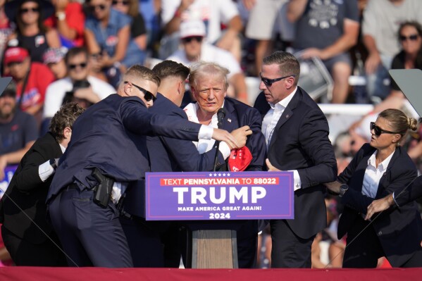 Republican presidential candidate former President Donald Trump is helped off the stage at a campaign event in Butler, Pa., on Saturday, July 13, 2024. (AP Photo/Gene J. Puskar)