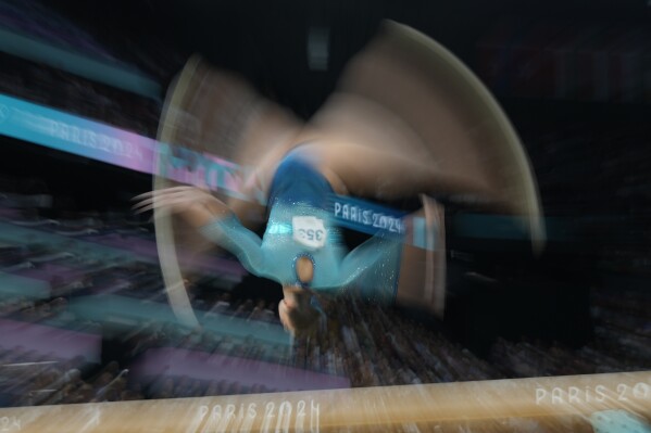 In this photo made with a slow shutter speed, Manila Esposito, of Italy, performs on the balance beam during the women's artistic gymnastics all-around finals in Bercy Arena at the 2024 Summer Olympics, Thursday, Aug. 1, 2024, in Paris, France. (AP Photo/Francisco Seco)