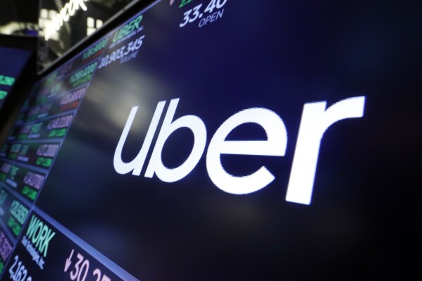 FILE - The Uber logo appears above a trading post on the floor of the New York Stock Exchange, Aug. 16, 2019. The ride sharing giant Uber and Chinese automaker BYD plan a partnership to introduce 100,000 BYD model EVs on the Uber platform in Europe and Latin America, eventually expanding to other markets, the companies announced. (AP Photo/Richard Drew, File)