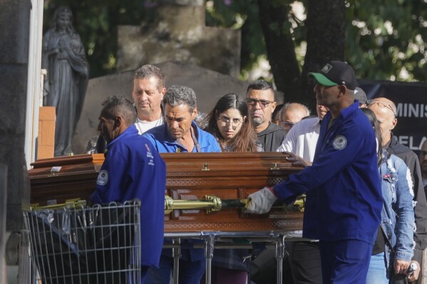 The coffin of Danilo Santos Romano, 35, is taken to his burial site at Penha Cemetery in Sao Paulo, Brazil, Monday, Aug. 12, 2024. Romano was the pilot of the plane that crashed into the backyard of a home in the city of Vinhedo on Aug. 9. (AP Photo/Andre Penner)