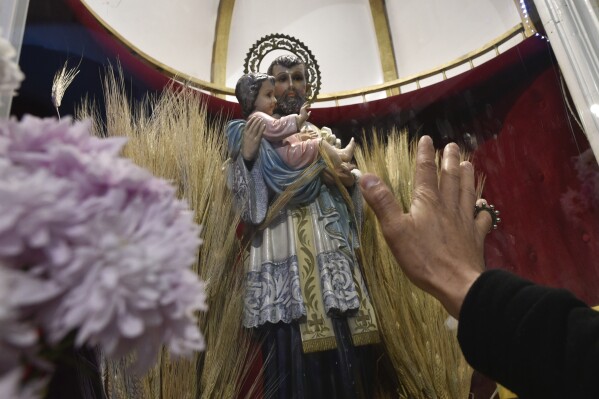 A person reaches out to the statue of Saint Cajetan inside San Cayetano church in Buenos Aires, Argentina, Wednesday, Aug. 7, 2024. Known as the patron saint of the unemployed, Catholics visit the church on the Italian Saint's feast day to pray for prosperity and work. (AP Photo/Gustavo Garello)