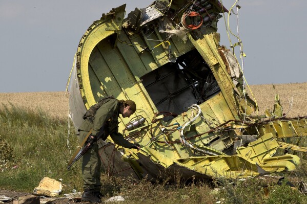 FILE - A pro-Russian rebel touches the MH17 wreckage at the crash site of Malaysia Airlines Flight 17, near the village of Hrabove, eastern Ukraine, on July 22, 2014. 298 people were killed as a Soviet-era Buk surface-to-air rocket launched from territory in eastern Ukraine controlled by pro-Russian rebels destroyed Malaysia Airlines Flight MH17. A 10-year commemoration ceremony at a monument near Schiphol, the airport the doomed flight left on its way to Kuala Lumpur will be held on July 17, 2014. (AP Photo/Vadim Ghirda, File)