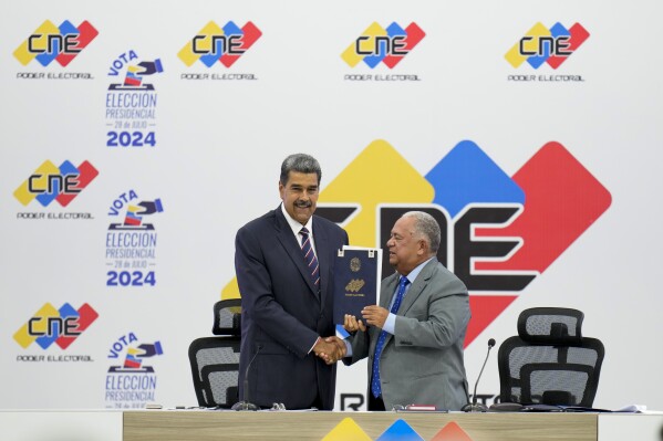 Venezuelan President Nicolas Maduro, left, receives certification from the President of the National Electoral Council (CNE) Elvis Amoroso that he won the presidential election, at the CNE in Caracas, Venezuela, Monday, July 29, 2024. (AP Photo/Matias Delacroix)