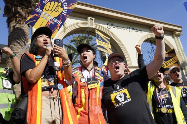 FILE - SAG-AFTRA captains Iris Liu, left, and Miki Yamashita, center, and SAG-AFTRA chief negotiator Duncan Crabtree-Ireland lead a cheer for striking actors outside Paramount Pictures studio, Nov. 3, 2023, in Los Angeles. Hollywood's video game performers voted to go on strike Thursday, July 25, 2024, throwing part of the entertainment industry into another work stoppage after talks for a new contract with major game studios broke down over artificial intelligence protections. (AP Photo/Chris Pizzello, File)