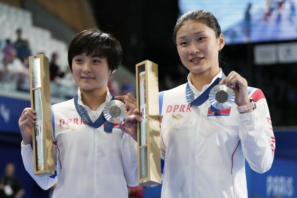 North Korea's Jo Jin Mi and Kim Mi Rae pose with their silver medal on the podium of the women's synchronised 10m platform diving final at the 2024 Summer Olympics, Wednesday, July 31, 2024, in Saint-Denis, France. (AP Photo/Jin Lee Man)