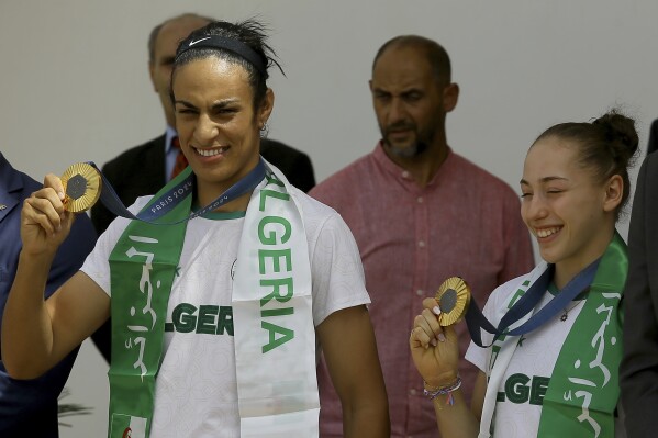 Gold medalist in the the women's 66 kg boxing Algeria's Imane Khelif, left, French-Algerian gymnast gold medalist in the uneven bars Kaylia Nemour show their medals after the 2024 Summer Olympics, Monday, Aug. 12, 2024, at Algiers airport, Algeria. (AP Photo/Anis Belghoul3