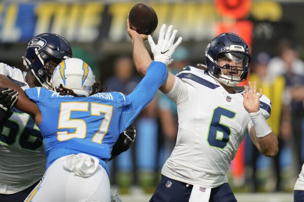 Seattle Seahawks quarterback Sam Howell (6) passes as Los Angeles Chargers linebacker Tre'Mon Morris-Brash (57) applies pressure during the first half of a preseason NFL football game in Inglewood, Calif., Saturday, Aug. 10, 2024. (AP Photo/Gregory Bull)