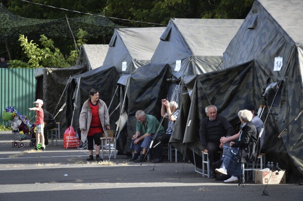 People evacuated from a fighting between Russian and Ukrainian forces in Kursk region sit next to tents at a temporary residence center in Kursk, Russia, Monday, Aug. 12, 2024. (AP Photo)