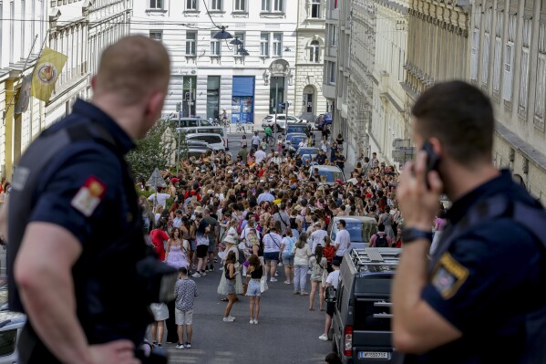 Austrian police officers watch swifts gathering in the city centre in Vienna on Thursday, Aug.8, 2024. Organizers of three Taylor Swift concerts in the stadium in Vienna this week called them off on Wednesday after officials announced arrests over an apparent plot to launch an attack on an event in the Vienna area such as the concerts. (AP Photo/Heinz-Peter Bader)