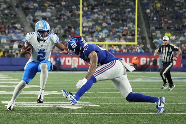 Detroit Lions quarterback Hendon Hooker (2) carries the ball against New York Giants linebacker Darrian Beavers (43) during the third quarter of an NFL football game, Thursday, Aug. 8, 2024, in East Rutherford, N.J. (AP Photo/Seth Wenig)