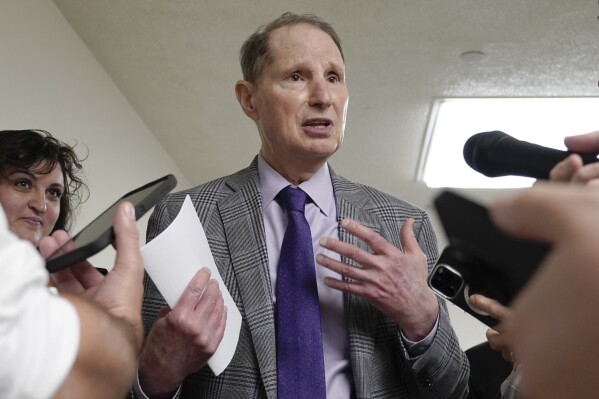 FILE - Sen. Ron Wyden, D-Ore., speaks with reporters at the U.S. Capitol, on Sept. 11, 2023, in Washington. Wyden is asking US regulators to look into a hiring practice being employed by the biggest technology companies to swallow up the talent and products of innovative AI startups without formally acquiring them.(AP Photo/Mariam Zuhaib, File)