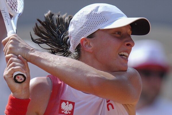 Iga Swiatek of Poland returns a shot to Anna Karolina Schmiedlova of Slovakia during their women's bronze medal match, at the 2024 Summer Olympics, Friday, Aug. 2, 2024, at the Roland Garros stadium in Paris, France. (AP Photo/Andy Wong)