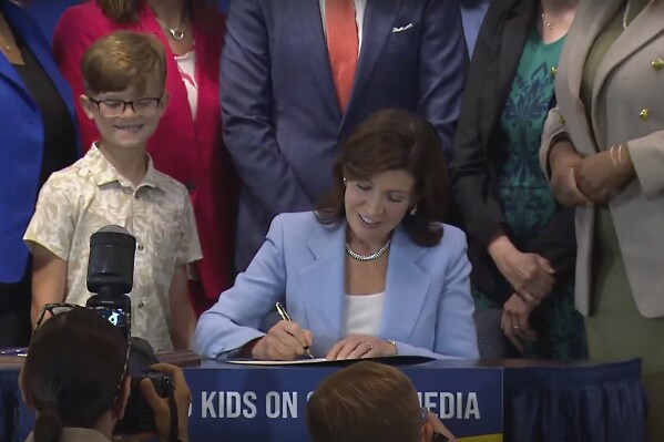 In this still image taken from video of the Office of the New York Governor, Gov. Kathy Hochul signs a bill, in New York, Thursday, June 20, 2024. Hochul signed a bill that would allow parents to block their children from getting social media posts suggested by a platform's algorithm, a move to limit feeds critics argue are addictive. (Office of the New York Governor via AP)