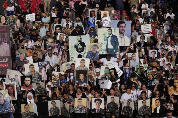 Relatives of the victims who were killed on the deadly 2020 Beirut port explosion, hold the portraits of loved ones, as they mark the fourth anniversary of Beirut's blast, in Beirut, Lebanon, Sunday, Aug. 4, 2024. (AP Photo/Hussein Malla)