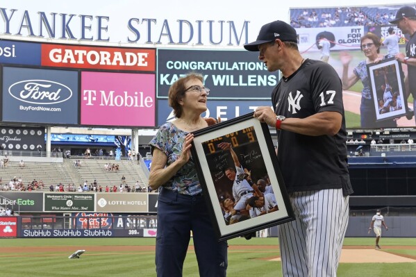 Yankees' Aaron Boone presents an autographed picture to Kathy Willens on June 28, 2021, in New York, of her picture of New York Yankees pitcher David Cone after Cone threw a perfect game. (Charles Wenzelberg/New York Post via AP)