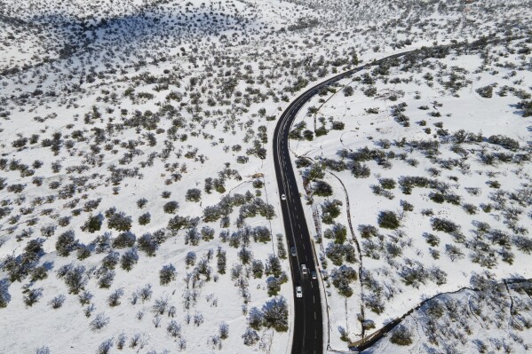 Cars drive along a snow-covered road in Santiago, Chile, Tuesday, Aug. 6, 2024. (AP Photo/Matias Basualdo)