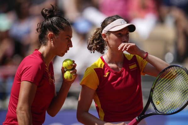 Cristina Bucsa and Sara Sorribes Tormo of Spain talk as they play against Linda Noskova and Karolina Muchova of the Czech Republic during their women's doubles bronze medal tennis match at the Roland Garros stadium, at the 2024 Summer Olympics, Sunday, Aug. 4, 2024, in Paris, France. (AP Photo/Louise Delmotte)