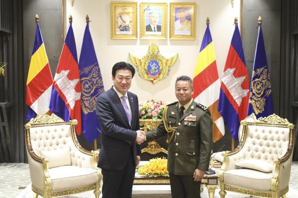 In this photo released by Cambodian Defense Ministry, Japanese Defense Minister Minoru Kihara, left, shakes with his Cambodian counterpart Tea Seiha at the Defense Ministry in Phnom Penh, Cambodia, Monday, Aug. 5, 2024. (Cambodian Defense Ministry via AP)