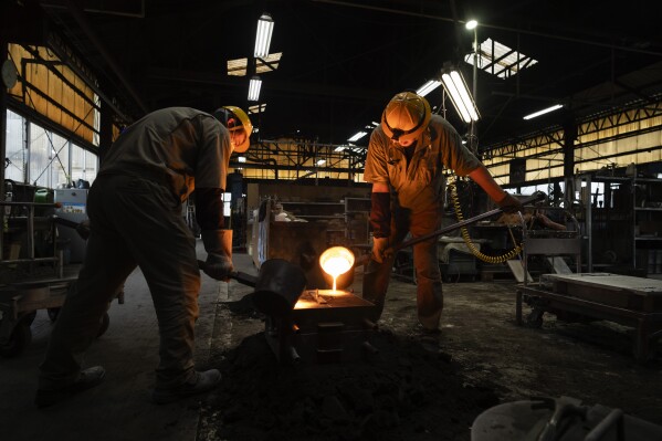 Craftsmen Suebsai Seksuk, left, a Thai native living in Japan, and Katsunori Suzuki pour molten iron into a mould while making a cast iron pot by hand at the Oigen foundry in Oshu, northeastern Japan, Thursday, May 16, 2024. (AP Photo/Hiro Komae)