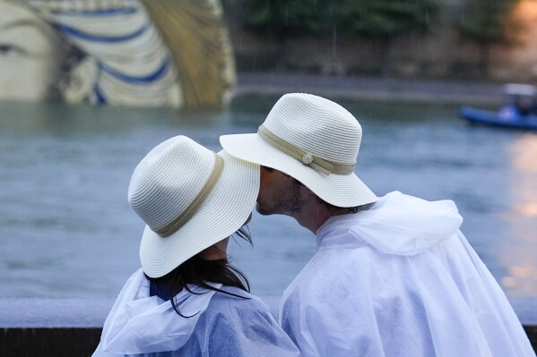 FILE - A couple kisses while on the Seine in Paris, France, during the opening ceremony of the 2024 Summer Olympics, Friday, July 26, 2024. Can kissing for six seconds a day lead to a more intimate relationship? That’s what couples therapists John and Julie Gottman say. They have taught thousands of couples therapists that an elongated kiss can help their clients. (AP Photo/Rebecca Blackwell, File)