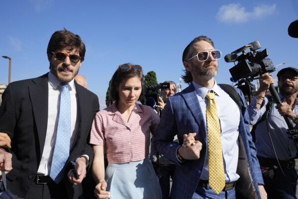 FILE - Amanda Knox arrives flanked by her husband, Christopher Robinson, right, and her lawyer, Luca Luparia Donati, left, at a court in Florence, Italy, June 5, 2024. (AP Photo/Antonio Calanni, File)