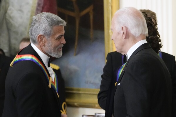 FILE - President Joe Biden shakes hands with actor, director and producer George Clooney during the Kennedy Center honorees reception at the White House in Washington, Dec. 4, 2022. Movie star and lifelong Democrat George Clooney is adding his voice to calls for Joe Biden to leave the presidential race. Clooney says in a New York Times opinion piece Wednesday that he loves Biden, but the party would lose the presidential race as well as any control in Congress with him as the nominee. (AP Photo/Manuel Balce Ceneta)