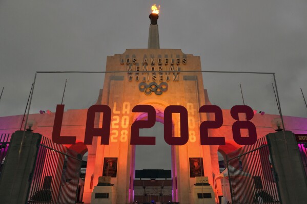 FILE - An LA 2028 sign is seen in front of the Olympic cauldron at the Los Angeles Memorial Coliseum on Sept. 13, 2017. (AP Photo/Richard Vogel, File)