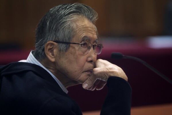 FILE - Peru's jailed, former President Alberto Fujimori, photographed through a glass window, attends his trial at a police base on the outskirts of Lima, Peru, June 28, 2016. Former President Fujimori, who was pardoned in December from his convictions for corruption and responsibility for the murder of 25 people, plans to run for Peru's presidency for the fourth time in 2026, his eldest daughter said Sunday, July 14, 2024. (AP Photo/Martin Mejia, File)