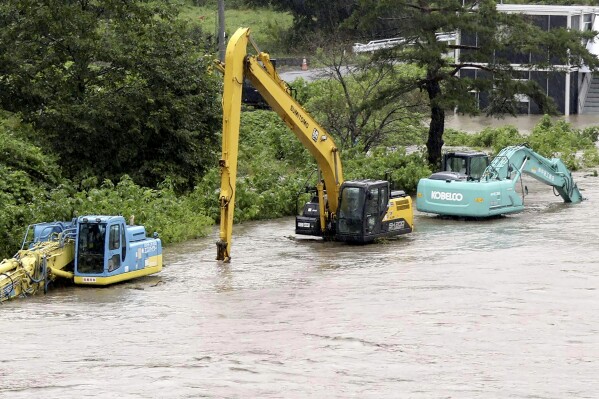 Construction vehicles are submerged due to a swollen river caused by a storm in Iwaizumi, Iwate prefecture, northern Japan, Monday, Aug. 12, 2024. (Kyodo News via AP)