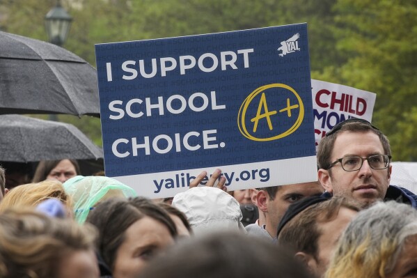 FILE - People listens as Texas Gov. Greg Abbott speaks on the north steps of the State Capitol to supporters at a Texas Public Policy Foundation Parent Empowerment rally, Tuesday, March 21, 2023 in Austin, Texas Abbott and his supporters are pushing to have a voucher system, also known as school choice. (Ricardo B. Brazziell/Austin American-Statesman via AP, FIle)