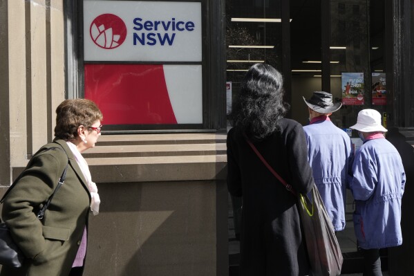 People walk in to a Services New South Wales office in Sydney, Tuesday, Aug. 6, 2024. (AP Photo/Rick Rycroft)