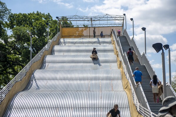 People ride the newly reopened Giant Slide at Belle Isle in Detroit on Friday, July 19, 2024. (Neo Hopkins/Detroit News via AP)