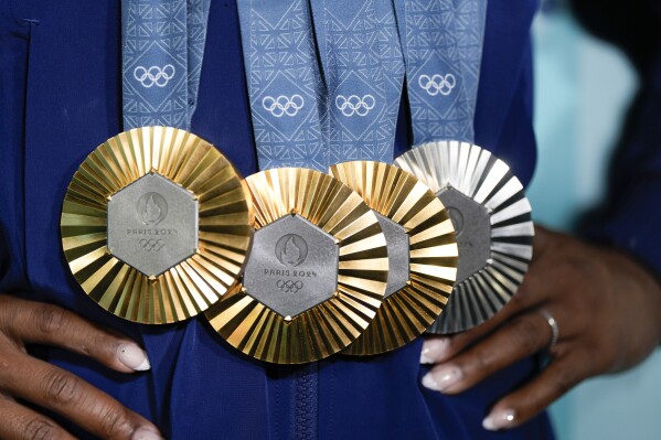 FILE - Simone Biles, of the United States, holds up her medals after the women's artistic gymnastics individual apparatus finals Bercy Arena at the 2024 Summer Olympics, Monday, Aug. 5, 2024, in Paris, France. (AP Photo/Charlie Riedel, File)