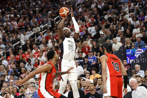 United States center Bam Adebayo (13) shoots between Canada power forward Trey Lyles (8) and point guard Andrew Nembhard (19) during the first half of an exhibition basketball game Wednesday, July 10, 2024, in Las Vegas. (AP Photo/Steve Marcus)