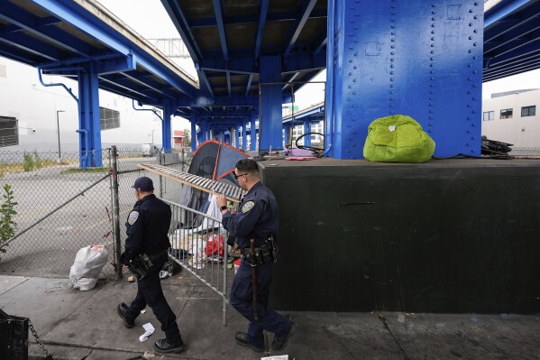 San Francisco Police officers walk past a homeless encampment Thursday, Aug. 1, 2024, in San Francisco. (AP Photo/Godofredo A. Vásquez)