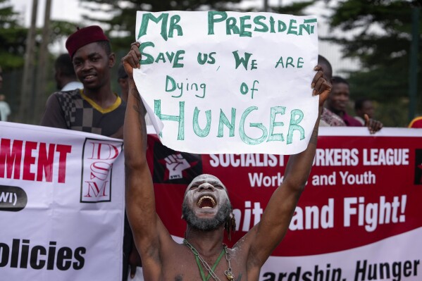 A man displays a placard as people protest over economic hardship on a street in Lagos, Nigeria, Monday, Aug 5, 2024. (AP Photo/Sunday Alamba)