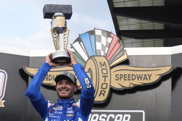 Kyle Larson holds the trophy after winning a NASCAR Cup Series auto race at Indianapolis Motor Speedway, Sunday, July 21, 2024, in Indianapolis. (AP Photo/Darron Cummings)