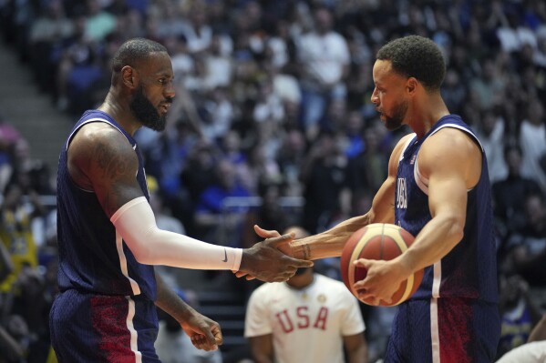 United States' forward LeBron James, left and United States' guard Stephen Curry shake hands during an exhibition basketball game between the United States and South Sudan, at the o2 Arena in London, Saturday, July 20, 2024. (AP Photo/Kin Cheung)