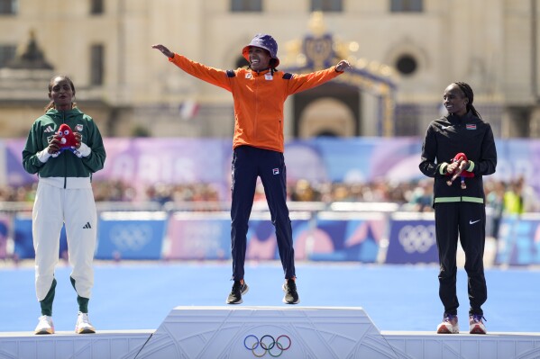 Gold medalist Sifan Hassan, of the Netherlands, center, silver medalist Ethiopia's Tigst Assefa, left, and bronze medalist Kenya's Hellen Obiri, right, pose for photographers during the victory ceremony at the end of the women's marathon competition at the 2024 Summer Olympics, Sunday, Aug. 11, 2024, in Paris, France. (AP Photo/Vadim Ghirda)