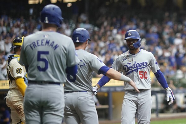 Los Angeles Dodgers' Mookie Betts (50) is congratulated by teammates after hitting a two-run home run during the third inning of a baseball game against the Milwaukee Brewers, Monday, Aug. 12, 2024, in Milwaukee. (AP Photo/Aaron Gash)