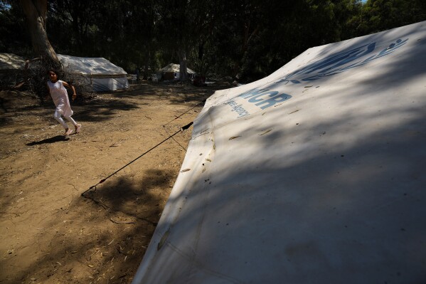 A girl runs next to the tents at a camp inside the U.N controlled buffer zone that divide the north part of the Turkish occupied area from the south Greek Cypriots at Aglantzia area in the divided capital Nicosia, Cyprus, Friday, Aug, 9, 2024. (AP Photo/Petros Karadjias)