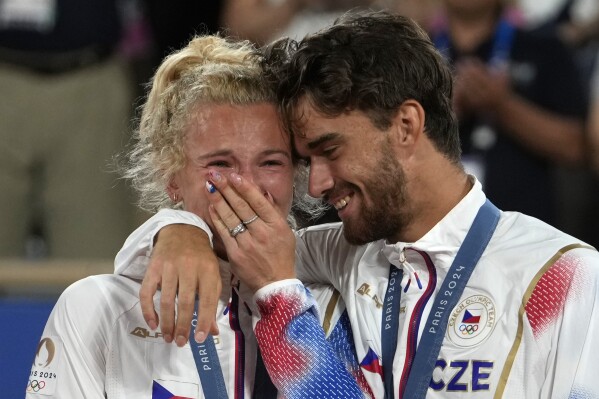 Czech Republic's Tomas Machac and Katerina Siniakova react on the podium after defeating China's Wang Xinyu and Zhang Zhizhen in the Mixed Doubles final tennis match at the Roland Garros stadium during the 2024 Summer Olympics, Friday, Aug. 2, 2024, in Paris, France. (AP Photo/Andy Wong)