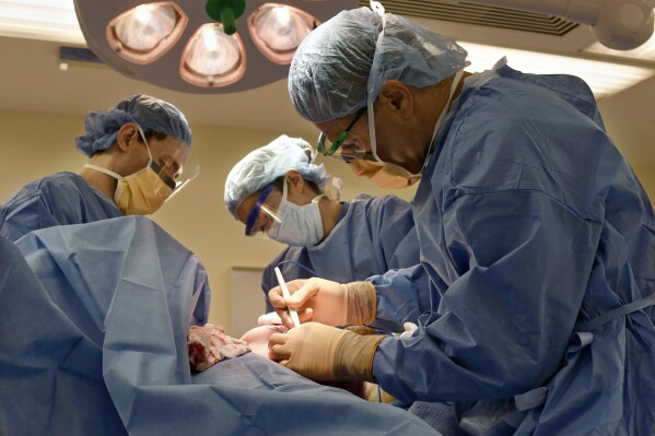 FILE - Surgeons perform a bilateral mastectomy on a transgender patient at a hospital in Boston on Friday, July 15, 2016. On Wednesday, July 3, 2024, a U.S. federal district court judge temporarily halted parts of a nondiscrimination rule that would have kept insurers and medical professionals from denying hormone therapy, gender transition surgeries and similar medical care for transgender people. (Christine Hochkeppel/Worcester Telegram & Gazette via AP, File)