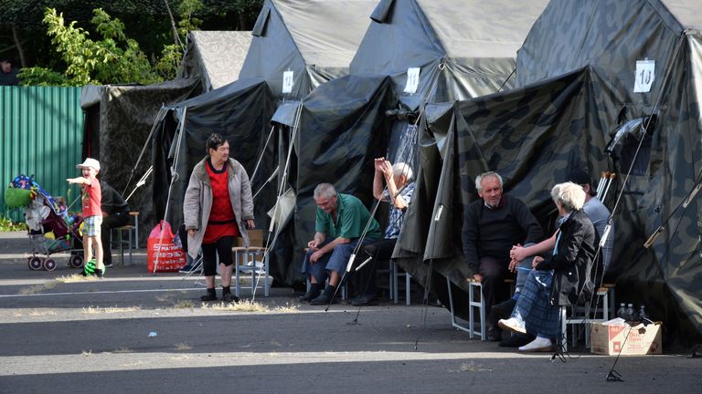 People evacuated from a fighting between Russian and Ukrainian forces in Kursk region sit next to tents at a temporary residence center in Kursk, Russia, Monday, Aug. 12, 2024. (AP Photo)